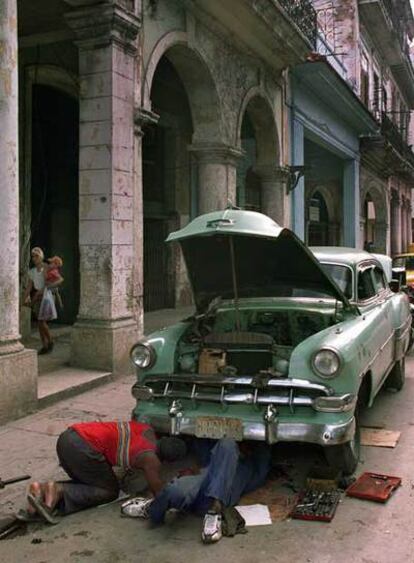 Dos cubanos reparan su coche en una calle de La Habana en 1999.