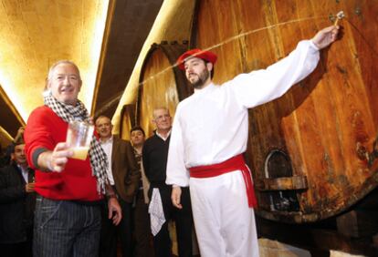 Un dantzari escancia la sidra de una barrica en el vaso del cocinero Karlos Arguiñano, ayer en Astigarraga.