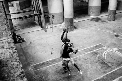 Uma criança e um homem jogam basquete na quadra que se encontra no térreo da torre.