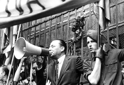 Carlos García Juliá sostiene una bandera en un mitin ultraderechista junto Blas Piñar, líder de Fuerza Nueva.