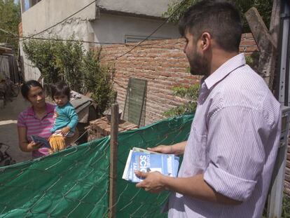 Un joven militante peronista entrega la papeleta de Scioli a una vecina del barrio Obligado de Bella Vista, en el Gran Buenos Aires.