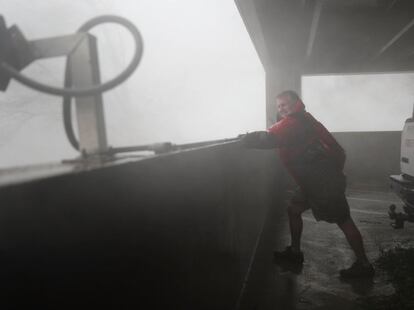 Chuck Cummins se cubre de los fuertes vientos durante el paso del huracán Michael.