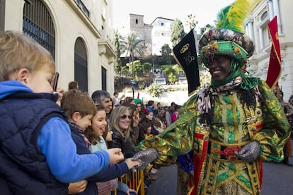 El Rey Baltasar saluda a unos niños durante la Cabalgata de los Reyes Magos de Oriente, que ha tenido lugar esta tarde en Málaga.