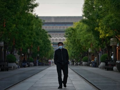 A man wearing a mask walks through the usually busy Qianmen shopping area in central Beijing.