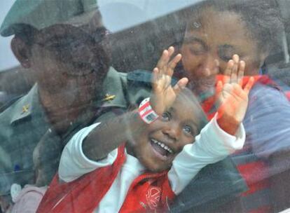 Uno de los niños llegados en la patera sonríe a un guardia civil a través de la ventanilla del automóvil en el que fue trasladado.