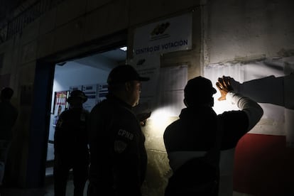 Apenas se colocaron las listas, los ciudadanos ayudados con la luz de sus teléfonos móviles buscan su nombre para votar este domingo, afuera de un centro de votación en Caracas.