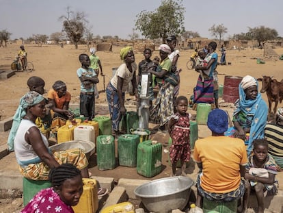 Mujeres y niños hacen cola para recoger agua en el campo de desplazados de Barsalogho, en Burkina Faso, en marzo de 2020.