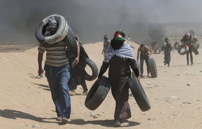 Palestinos cargan con neumáticos para ser quemados durante las protestas del 70 aniversario de la 'Nakba', en la Franja de Gaza. 