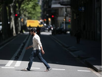 Un home creua el carril lateral de la Gran Via de Barcelona, on es tallarà el trànsit per donar espai als vianants.