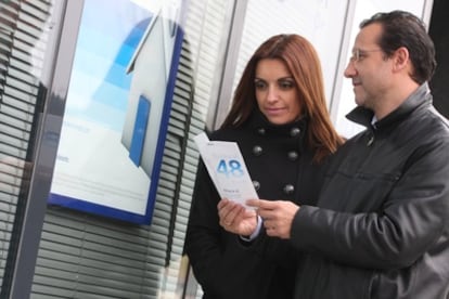 Una pareja observa publicidad de una entidad bancaria para adquirir una casa.