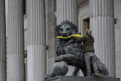 Fotografía facilitada por Greenpeace de una activista amordazando uno de los leones que presiden la fachada del Congreso de los Diputados en Madrid, como acto de protesta pacífica contra el anteproyecto de Ley de Protección de la Seguridad Ciudadana.