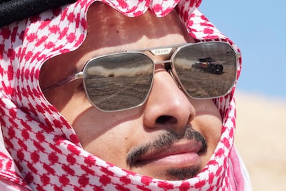 Un coche se refleja en las lentes de las gafas de sol de un espectador, durante la novena etapa del Dakar.