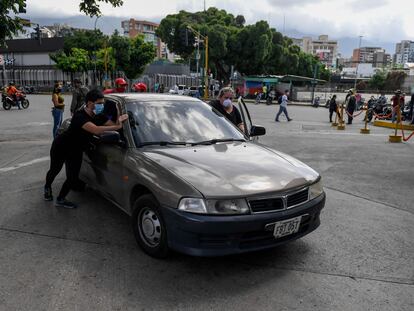 Varias personas empujan un coche para cargar gasolina en Caracas (Venezuela), este lunes.