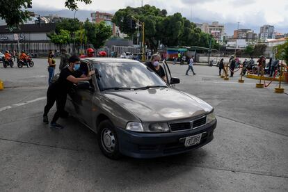 Varias personas empujan un coche para cargar gasolina en Caracas (Venezuela), este lunes.