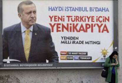 Una turca revisa su móvil delante de un cartel con la fotografía del primer ministro turco, Recep Tayyip Erdogan. EFE/Archivo