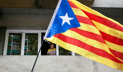 Una mujer mira desde una ventana la celebración de la Diada en Barcelona.