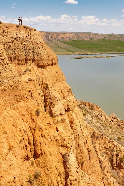 Barrancas de Burujón (Toledo), el Gran Cañón del Tajo. El río Tajo surca un cañón grandecito, de 200 metros de profundidad, en su curso alto, entre Cuenca y Guadalajara. Sin embargo, el paraje que recuerda al Gran Cañón del Colorado (EE UU), por sus formas y colores, se encuentra a poco menos de 100 kilómetros de Madrid y a 28 de Toledo, río abajo. Las Barrancas de Burujón están señalizadas en el kilómetro 24 de la carretera CM-4000. Allí mismo, escondidos tras los álamos del arroyo de Alcubillete, hay un restaurante y un amplio aparcamiento donde dejar el coche para seguir avanzando a pie por una pista de tierra que describe un círculo de 4,5 kilómetros y permite contemplar desde tres miradores el río represado en el embalse de Castrejón y las cárcavas arcillosas que, a modo de media luna, ciñen su orilla norte ofreciendo un alucinante cuadro de vértigo y rojos crepusculares. En el mirador del Cambrón, el primero y más alto (a 100 metros sobre las aguas), un panel informativo habla de los procesos geológicos que han dado forma a este paraje durante los últimos 23 millones de años. Vale: en el Gran Cañón los miradores están a más de 2.000 metros de altura y en sus estratos se leen otros tantos millones de años. Seamos un poco imaginativos. O mucho. En la última película de José Luis Cuerda, ‘Tiempo después’ (2018), el paisaje descarnado de la Barrancas es el mundo postapocalíptico del año 9971.