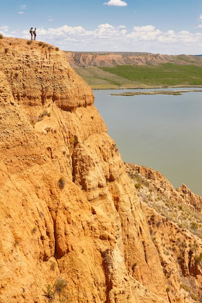 Barrancas de Burujn (Toledo), el Gran Ca?n del Tajo. El ro Tajo surca un ca?n grandecito, de 200 metros de profundidad, en su curso alto, entre Cuenca y Guadalajara. Sin embargo, el paraje que recuerda al Gran Ca?n del Colorado (EE UU), por sus formas y colores, se encuentra a poco menos de 100 kilmetros de Madrid y a 28 de Toledo, ro abajo. Las Barrancas de Burujn estn se?alizadas en el kilmetro 24 de la carretera CM-4000. All mismo, escondidos tras los lamos del arroyo de Alcubillete, hay un restaurante y un amplio aparcamiento donde dejar el coche para seguir avanzando a pie por una pista de tierra que describe un crculo de 4,5 kilmetros y permite contemplar desde tres miradores el ro represado en el embalse de Castrejn y las crcavas arcillosas que, a modo de media luna, ci?en su orilla norte ofreciendo un alucinante cuadro de vrtigo y rojos crepusculares. En el mirador del Cambrn, el primero y ms alto (a 100 metros sobre las aguas), un panel informativo habla de los procesos geolgicos que han dado forma a este paraje durante los ltimos 23 millones de a?os. Vale: en el Gran Ca?n los miradores estn a ms de 2.000 metros de altura y en sus estratos se leen otros tantos millones de a?os. Seamos un poco imaginativos. O mucho. En la ltima pelcula de Jos Luis Cuerda, Tiempo despus (2018), el paisaje descarnado de la Barrancas es el mundo postapocalptico del a?o 9971.