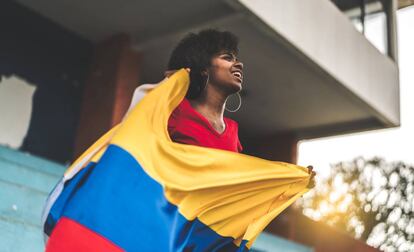 Una mujer sostiene una bandera de Colombia.
