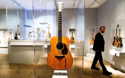 Un asistente observa una guitarra tocada por Elvis Presley (centro) junto a la batería de Ringo Star (a la izquierda).  