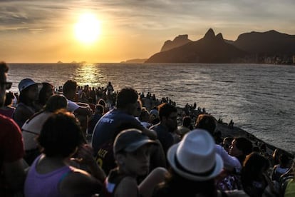 Pessoas observam o pôr do sol na pedra do Arpoador, no Rio de Janeiro.