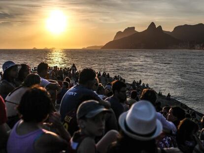 Pessoas observam o pôr do sol na pedra do Arpoador, no Rio de Janeiro.