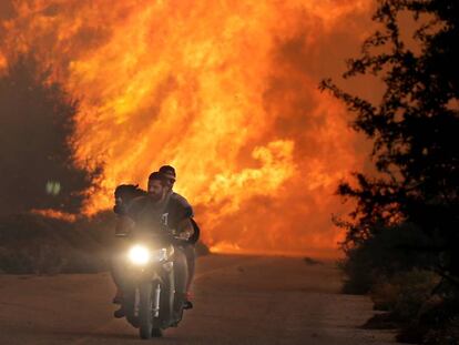 Dos personas huyen con un perro de un incendio en el norte de Atenas el pasado día 14.