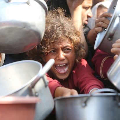 A child reacts surrounded by pots as Palestinians wait to receive food from a charity kitchen in Khan Younis, southern Gaza Strip, August 21, 2025. REUTERS/Hatem Khaled     TPX IMAGES OF THE DAY     