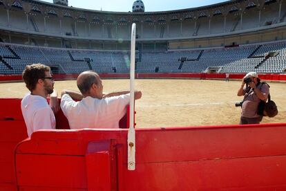 Dos turistas se hacen fotografías en la plaza de toros Monumental de Barcelona, vacía, el día siguiente de la celebración de la última corrida en el coso catalán.