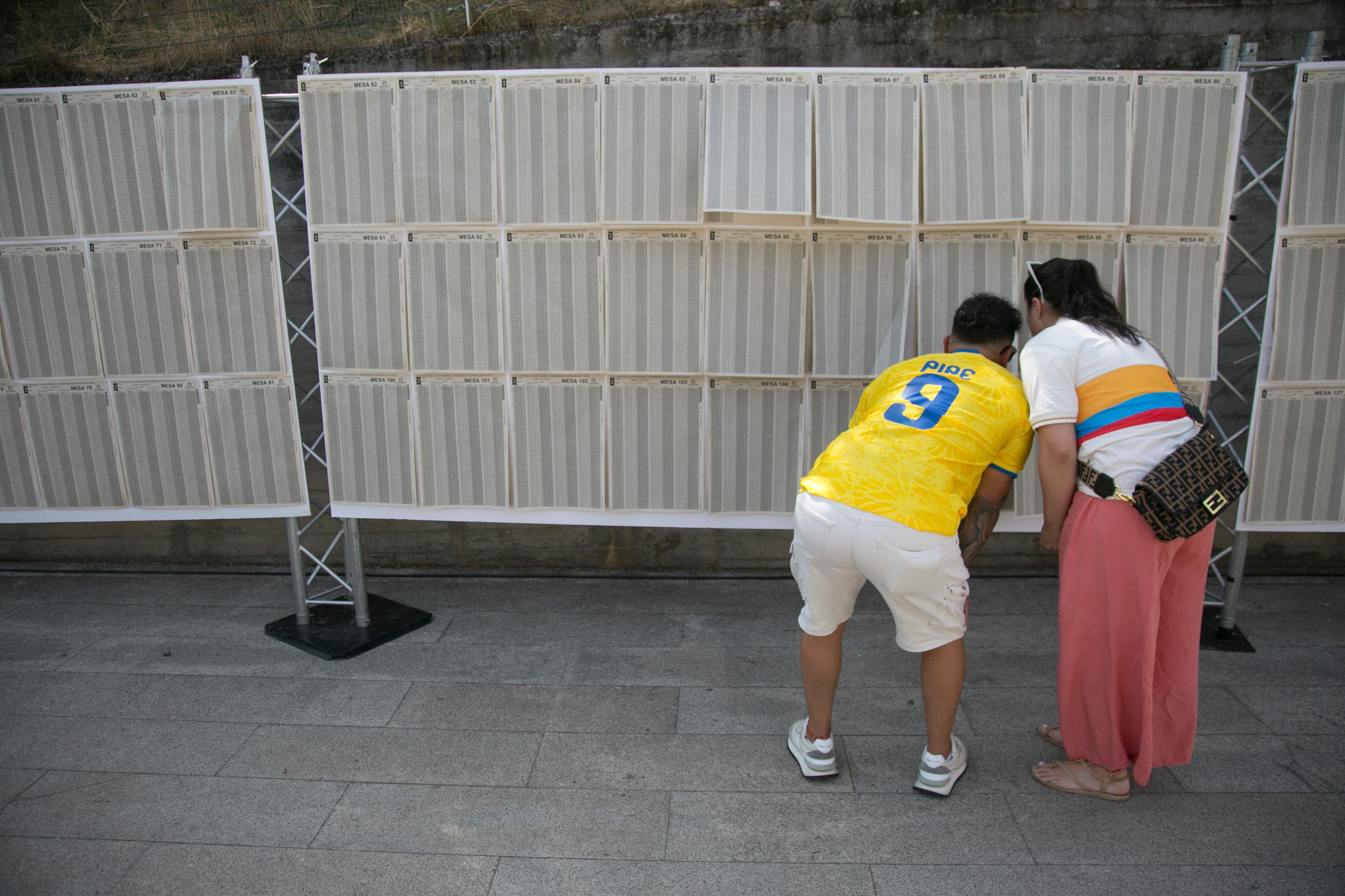 Una pareja verifica cuál es su mesa de votación en el Pabellón de Convenciones de la Casa de Campo en Madrid, el 20 de junio de 2026.
