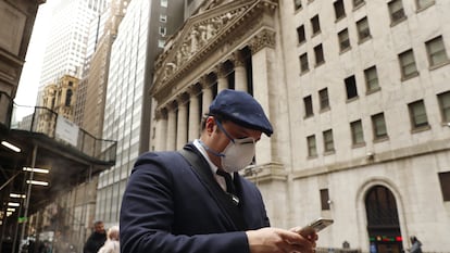 FILE PHOTO: A man wears a protective mask as he walks past the New York Stock Exchange on the corner of Wall and Broad streets during the coronavirus outbreak in New York City, New York, U.S., March 13, 2020. REUTERS/Lucas Jackson/File Photo