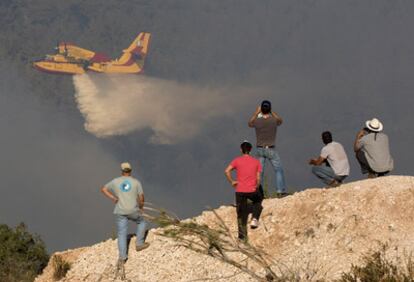 Un grupo de residentes sigue las labores de extinción de un hidroavión en Ein Hod, al norete de Israel.