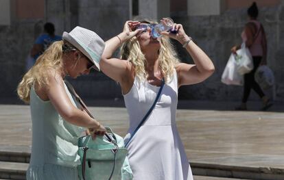 Dos turistas se hidratan ante las elevadas temperaturas.