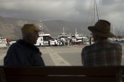 Un grupo de turistas llegados al puerto de la Caleta del Sebo, en la isla de La Graciosa, son observados por vecinos del lugar.