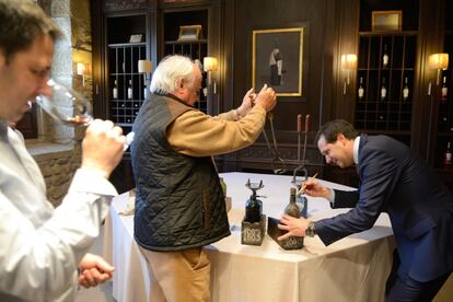 Jon Andoni Rementería cata un vino a la izquierda mientras Francisco Hurtado de Amézaga corta el cuello a una botella de 1883. 