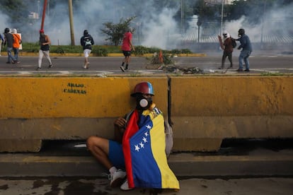 Un manifestante se protege detrás de un muro durante una nueva jornada de protestas en Caracas (Venezuela).
