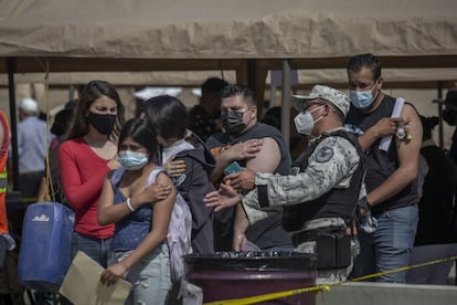 Personas son asistidas por un elemento de la Guardia Nacional durante las jornadas de vacunación.