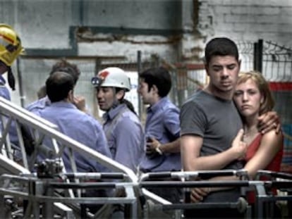 Una pareja se abraza frente al edificio derrumbado en L'Hospitalet, mientras los equipos de emergencia trabajan en la zona. PLANO GENERAL