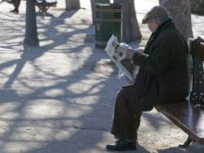 Un anciano lee el periódico en un parque de Madrid.