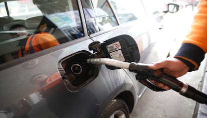 Un treballador omple de combustible un vehicle en una gasolinera.