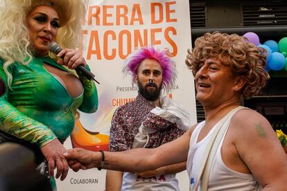 Chumina Power, presentadora de la carrera, saluda a uno de los ganadores de la carrera de tacones, en la calle de Pelayo, Madrid.