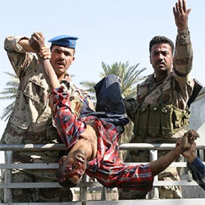 Soldados iraquíes sujetan el cuerpo de un hombre muerto en el atentado.