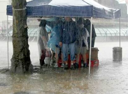 Varias personas se refugiaban, ayer, del fuerte aguacero bajo un toldo del Arenal bilbaíno.