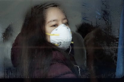 Una mujer con mascarilla dentro de un autobús en Pekín (China).