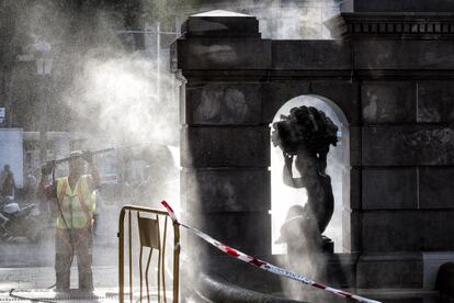 Un operari netejant una escultura a la plaça de Catalunya de Barcelona.