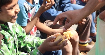 Un voluntario de una ONG reparte comida a niños. 