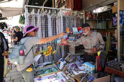 El dueño palestino de una tienda recibe una flor entregada por activistas por la paz israelíes durante el Desfile de las Flores.