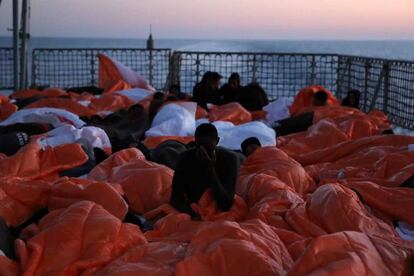 Migrantes tapados con mantas se disponen a pasar la noche en cubierta.