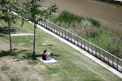 Una mujer descansa en una zona de césped en Madrid Río, abierto en la fase 1 de la desescalada.
25/05/2020