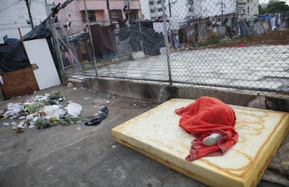 Pessoa dorme em espuma de colchão próxima ao lixo, na cracolândia.